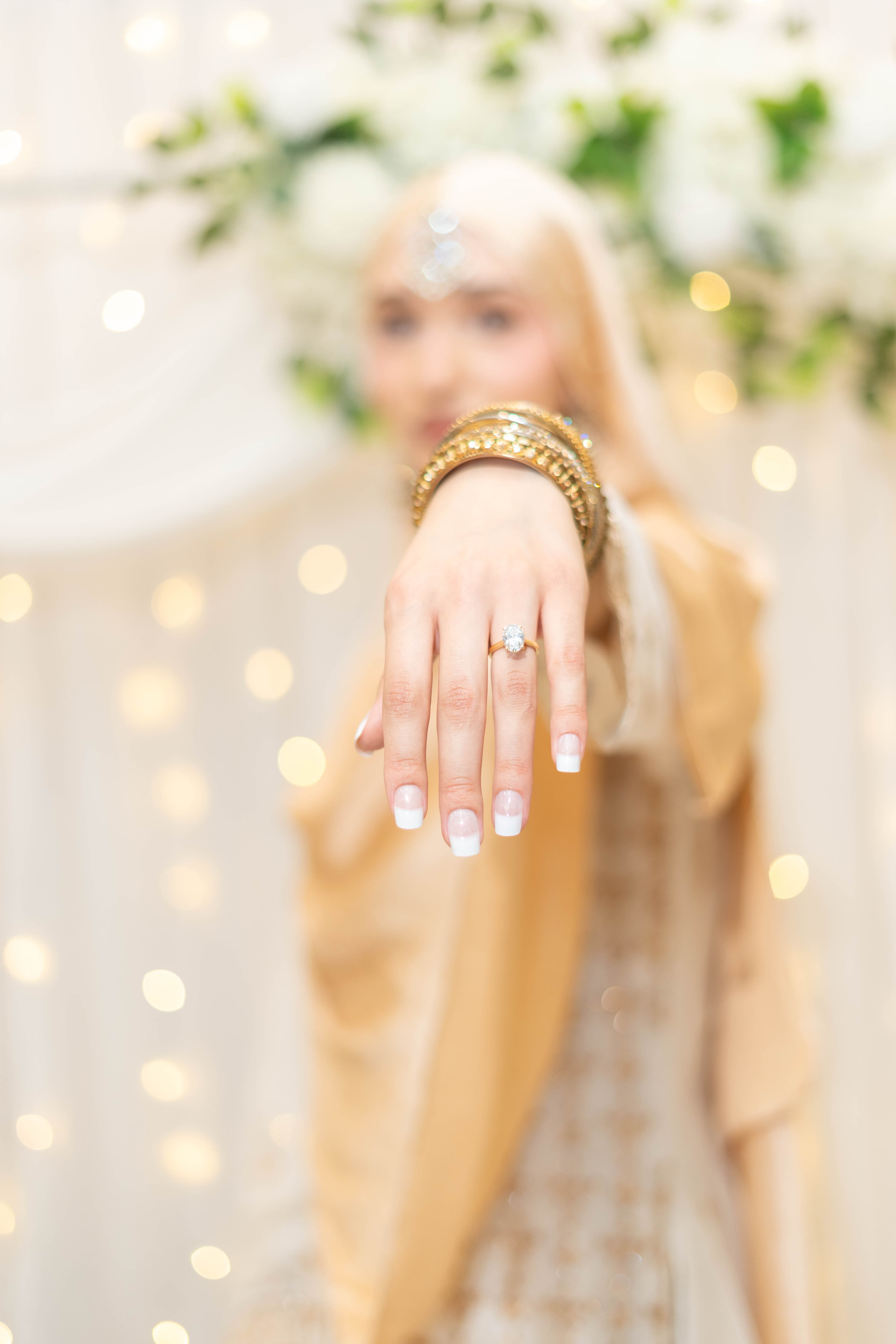 Extended hand displaying a ring and stacked gold bangles.