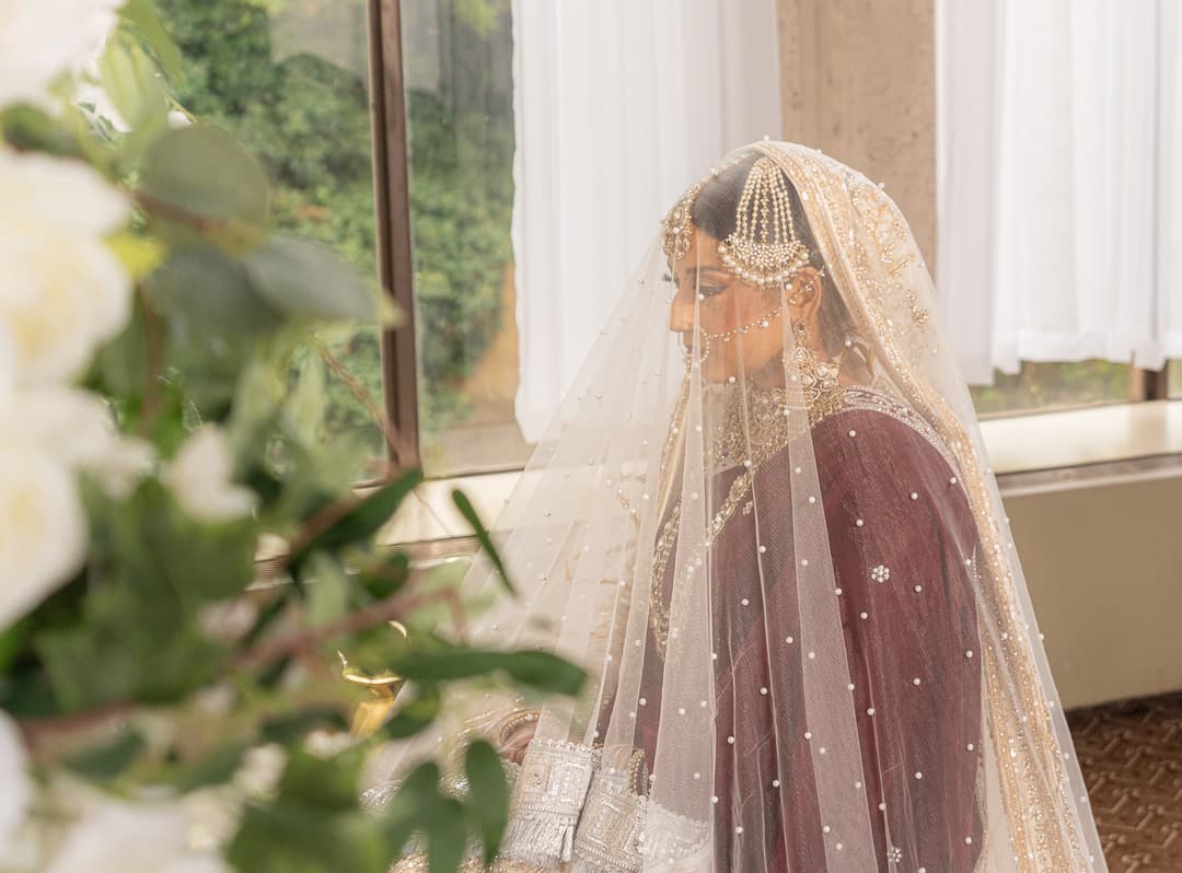Bride photographed through white flowers during a quiet moment before the ceremony.